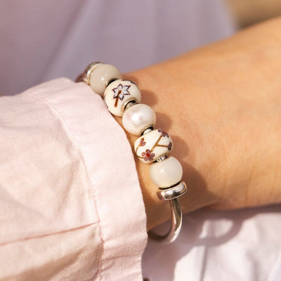 Close-up of a person wearing a bracelet with white beads and a blurred background
