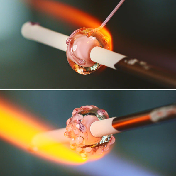 Molten glass is shaped into a pink glass jewellery bead on a stick made of steel