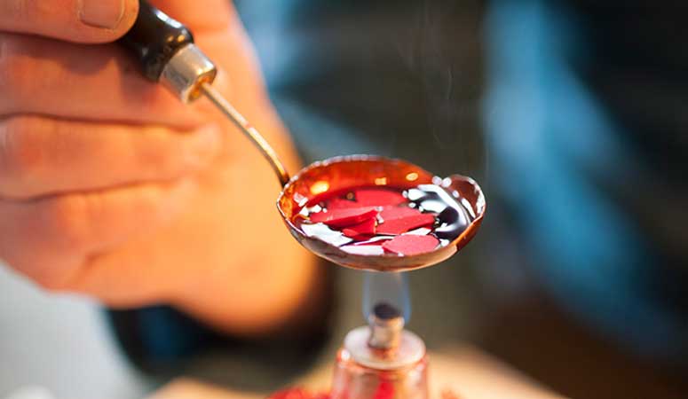 Wax being melted by hand, the first step in casting a silver bead