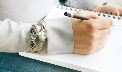model writing wearing two Trollbeads bangels adorned with beads