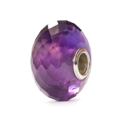 The Amethyst is a deep purple gemstone bead with a faceted shape. 